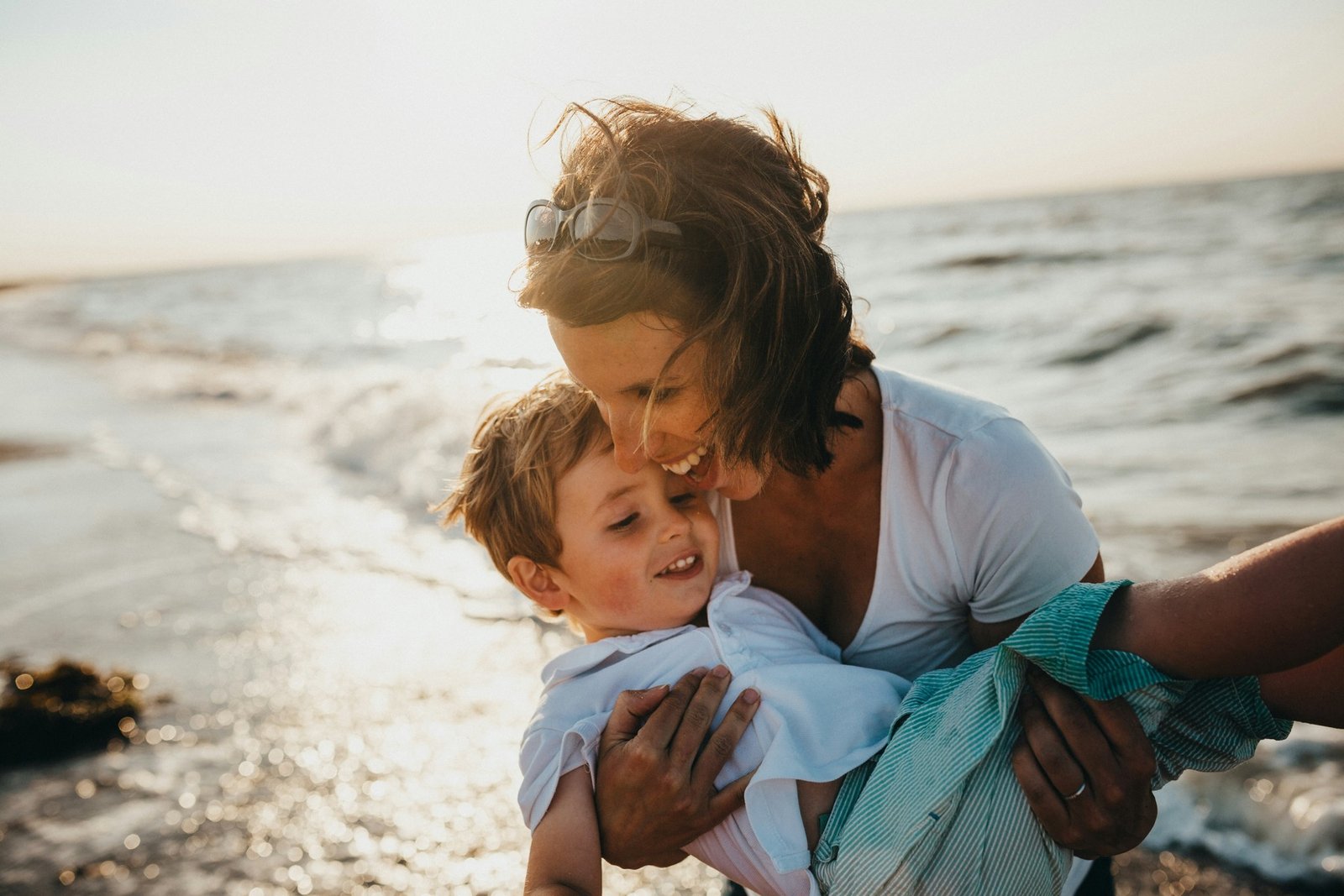 A mother laughing with her son at the beach