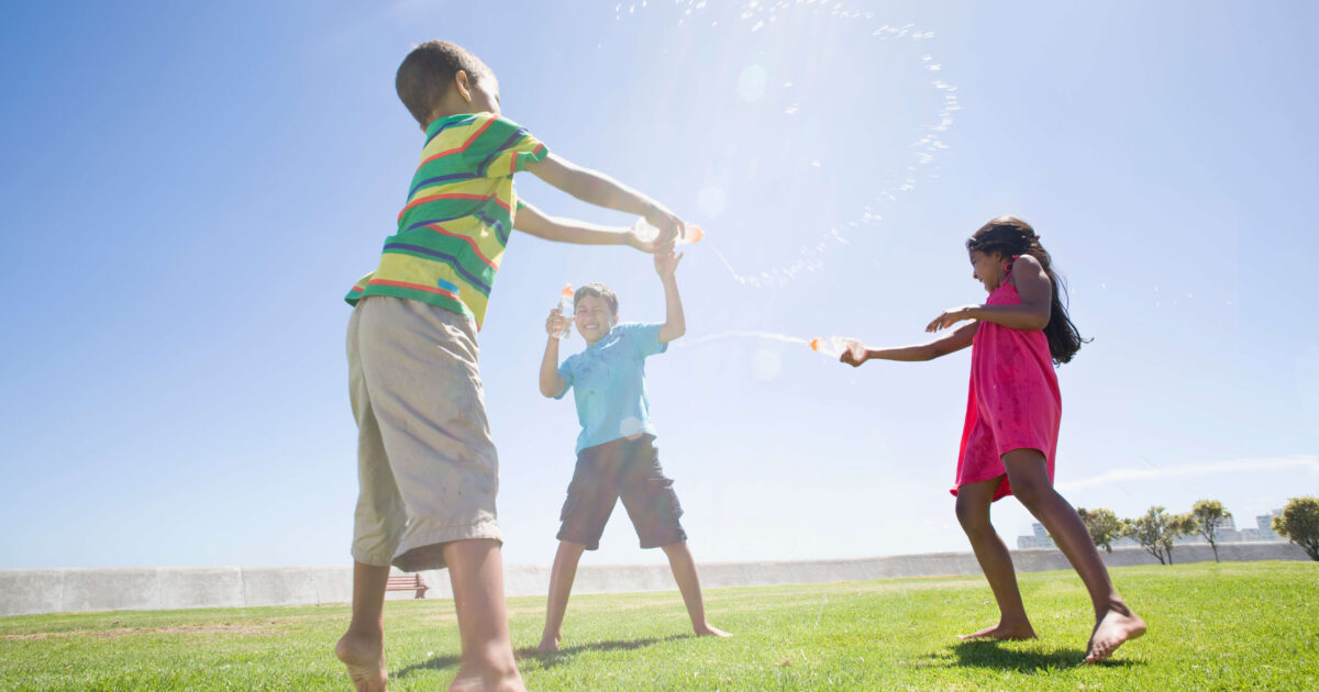 children squirting water at each other using plastic cups