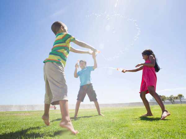 children squirting water at each other using plastic cups