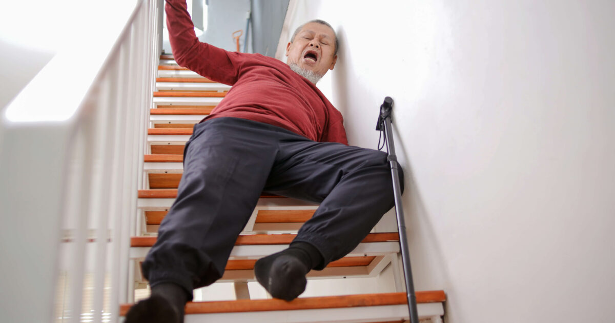 Elderly asian man lying on staircase after slip and fall