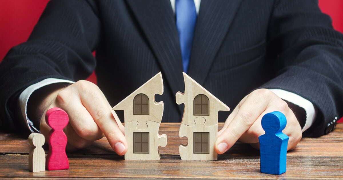 Lawyer splitting a paper house indicating property division after a divorce