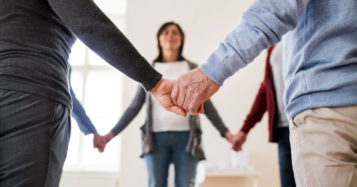 People holding their hands together as in a group class