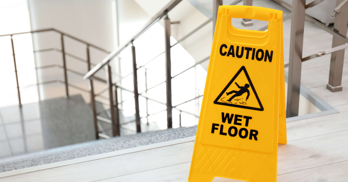 Safety sign with phrase caution wet floor near stairs