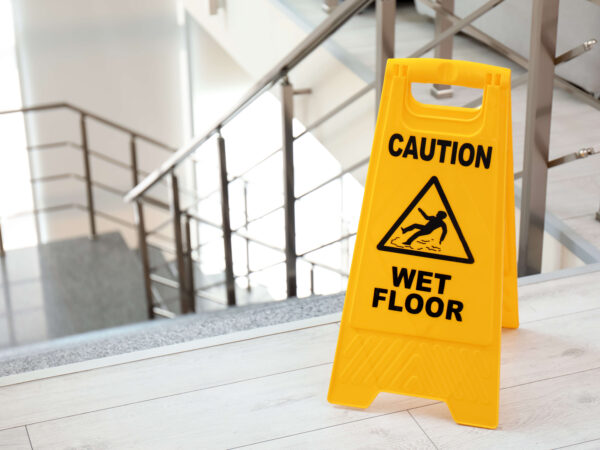 Safety sign with phrase caution wet floor near stairs
