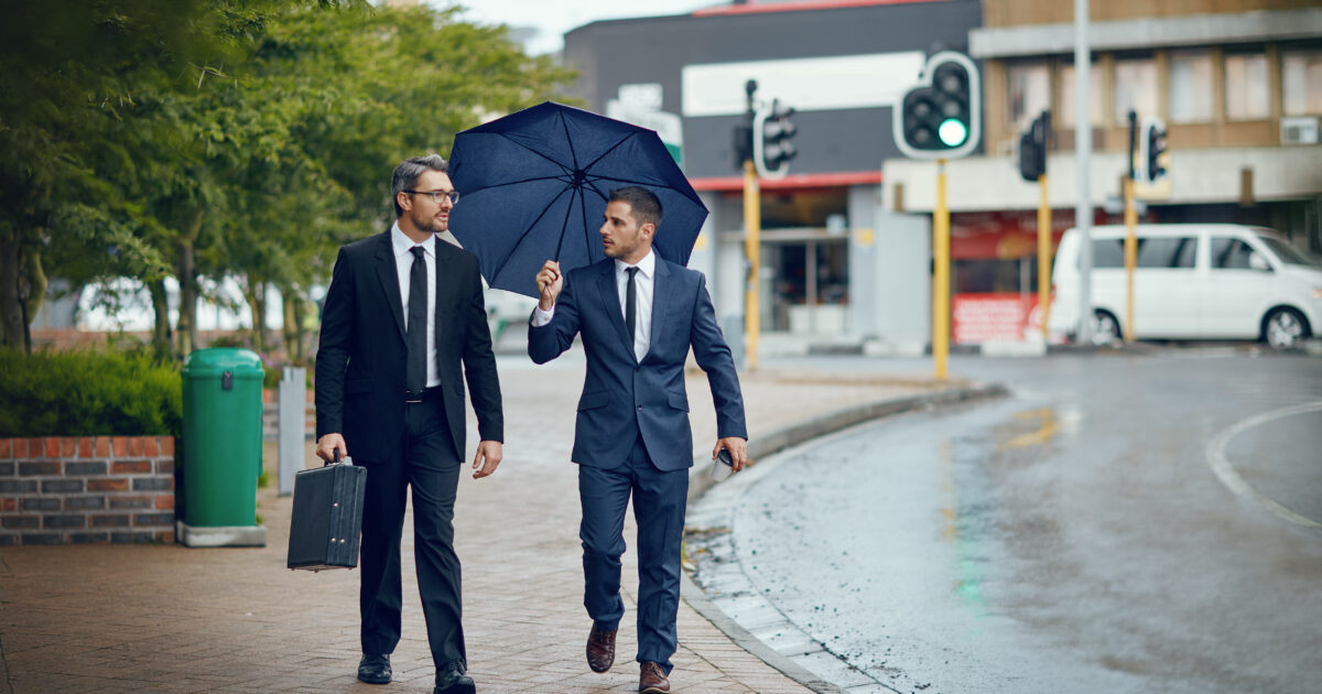 Shot-of-two-corporate-businessmen-travelling-through-the-city-on-a-rainy day.