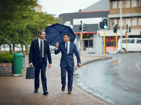 Shot-of-two-corporate-businessmen-travelling-through-the-city-on-a-rainy day.