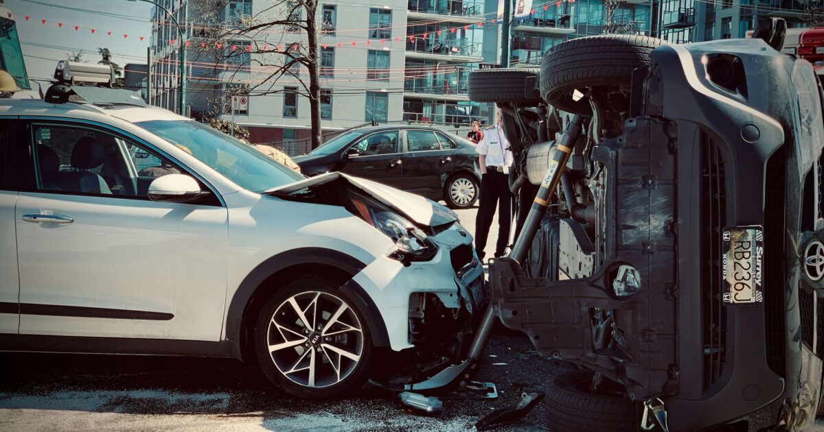 Two cars crash in a street, a building in the background