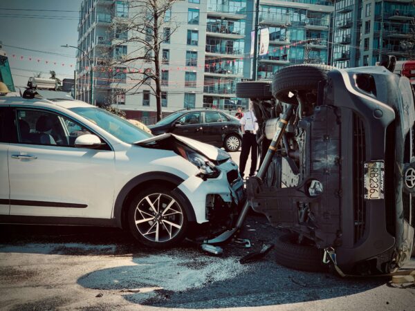 Two cars crash in a street, a building in the background