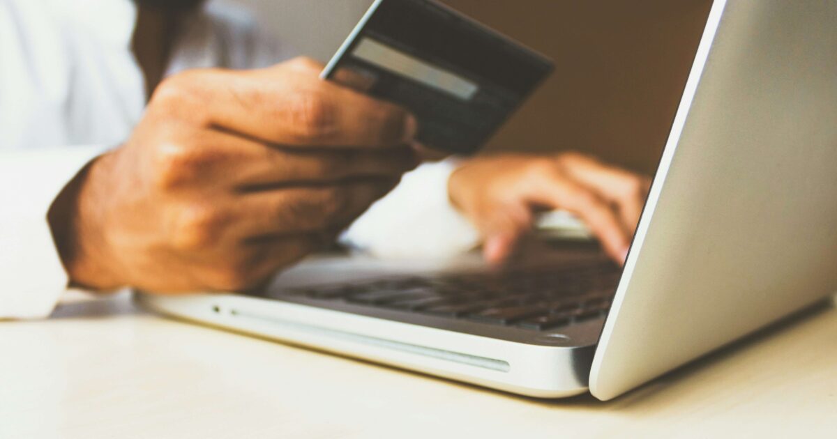 Men holding a credit card on his hand while trying to do an online payment with his computer