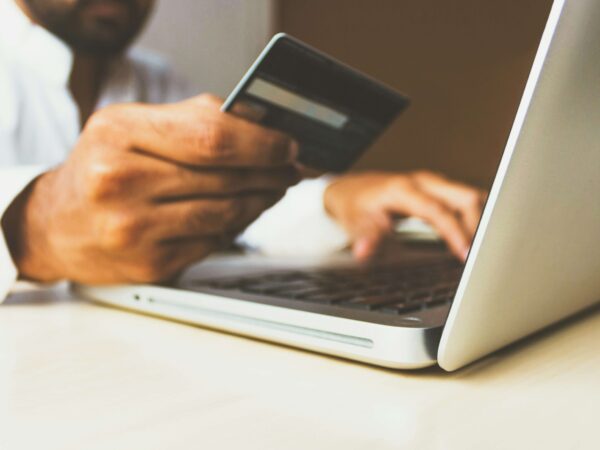 Men holding a credit card on his hand while trying to do an online payment with his computer